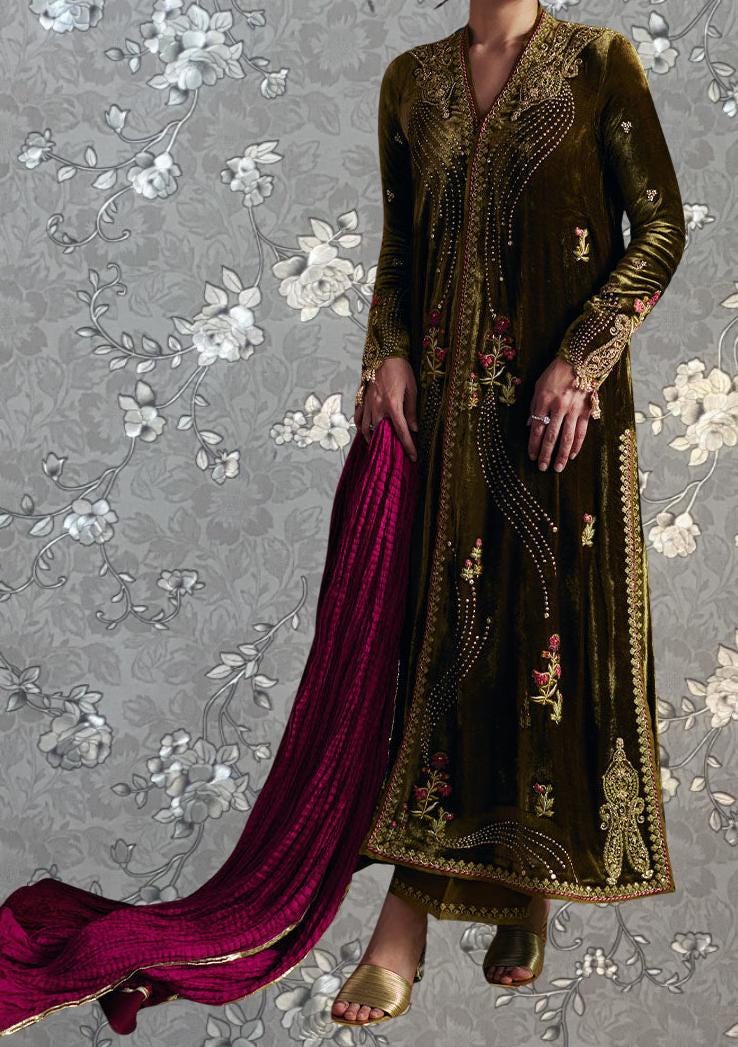 A person wearing a long, ornate gold and black velvet dress with intricate embroidery and a matching pink shawl draped over their shoulders.