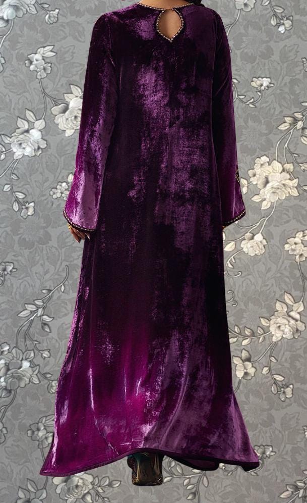 a person wearing a long, purple velvet dress with a floral pattern on the background.