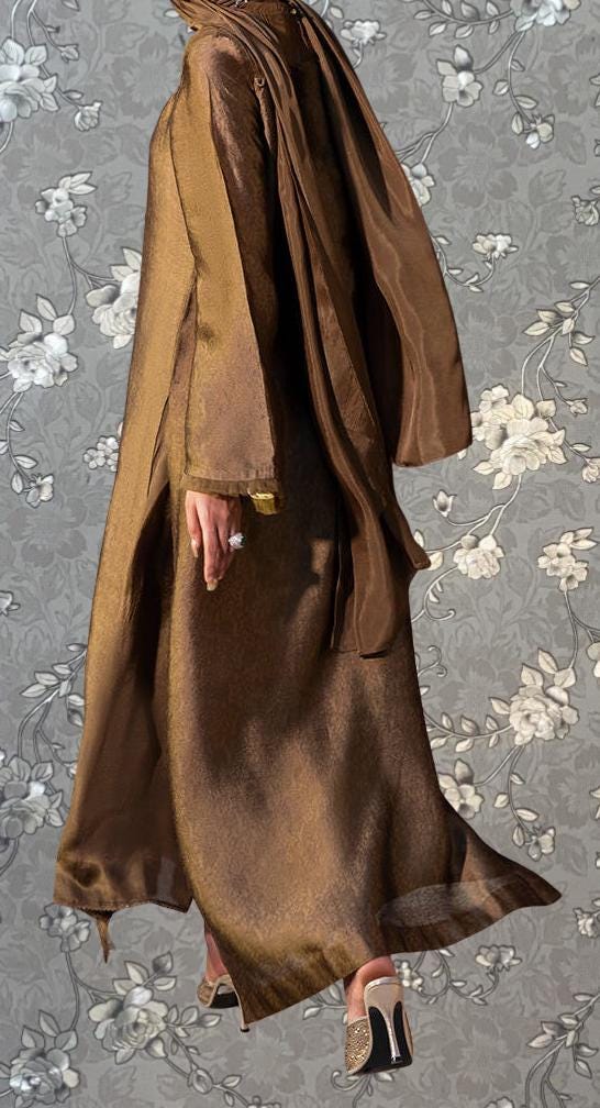 A person wearing a long brown robe and high heels stands against a gray floral background.