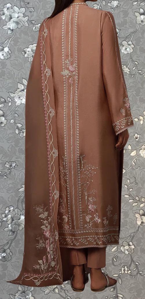 a person wearing a long, brown dress with intricate embroidered patterns on the back and sides. The dress has a long, flowing cape that extends behind the person. The background features a floral pattern, which complements the overall design of the dress.