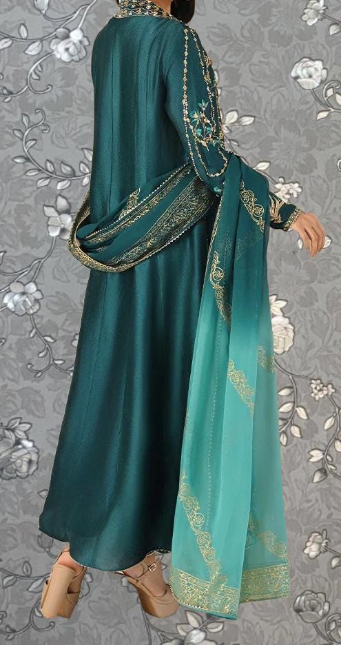 A person wearing a long, green dress with gold embroidery and a matching green shawl draped over the shoulders.