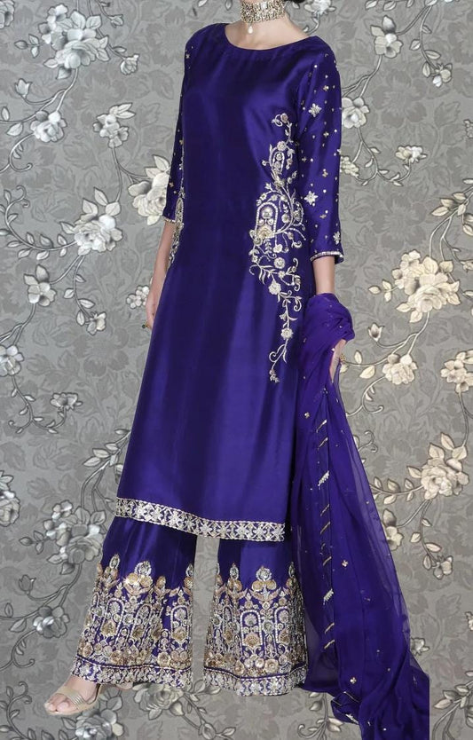 A woman wearing a long, purple dress with intricate gold embroidery and a matching skirt.