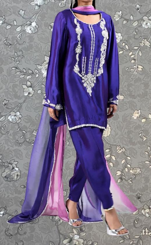 A woman wearing a purple and pink dress with intricate embroidery and a matching scarf.