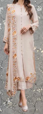 A woman wearing a long, light pink dress with intricate floral embroidery on the sleeves and hem.