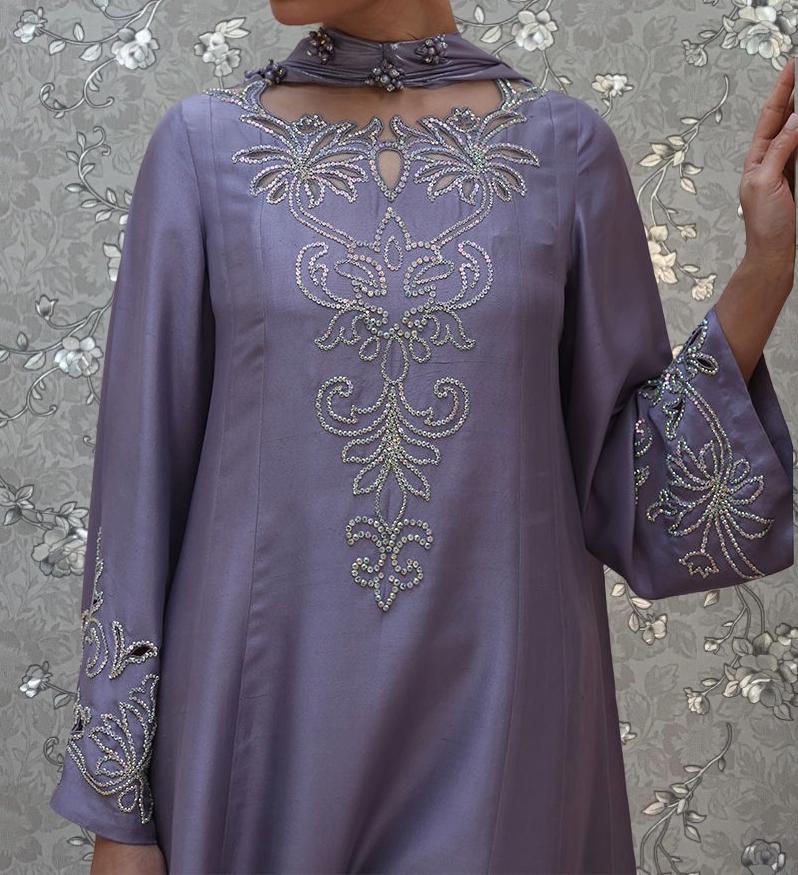 A close-up of a woman wearing a purple dress with intricate embroidered designs.