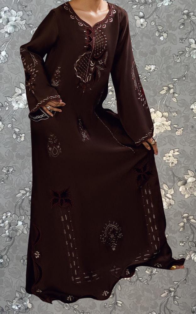 A woman wearing a long, brown dress with intricate embroidery and floral patterns.