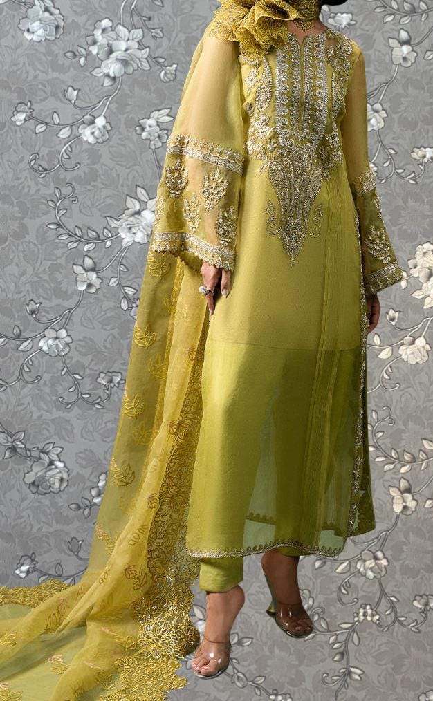 A woman wearing a long, yellow dress with intricate embroidery and a matching yellow shawl.