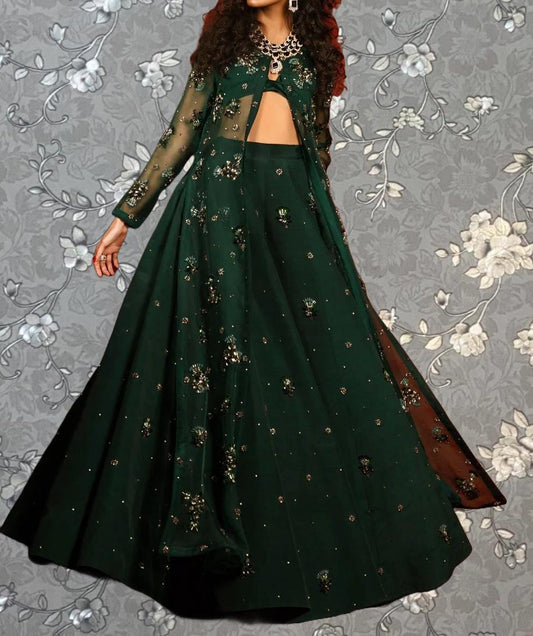 A woman wearing a long, green dress with intricate embroidery and a matching jacket.