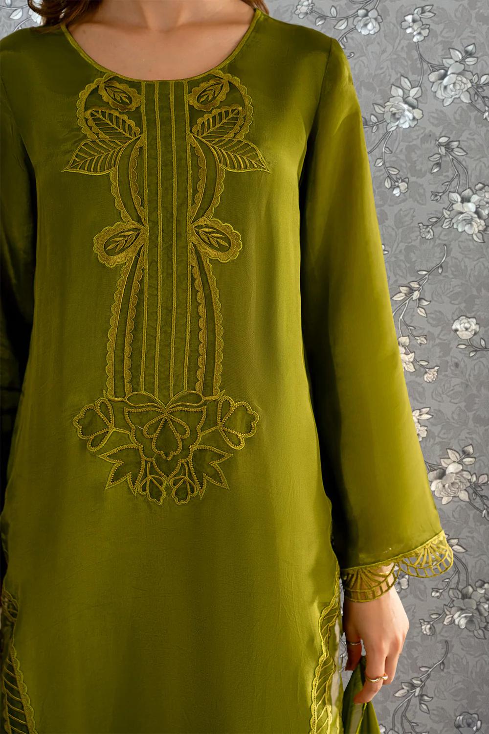 A close-up of a woman wearing a green dress with intricate embroidered designs on the front.