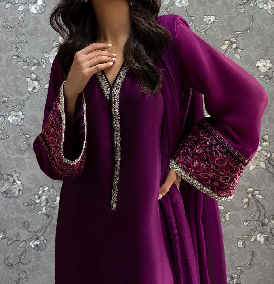 A woman wearing a purple dress with intricate embroidery on the sleeves and a matching purple shawl draped over her shoulders.
