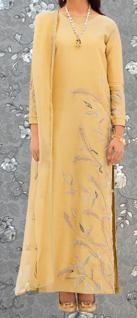 A woman wearing a long, yellow dress with intricate embroidered designs on the front.