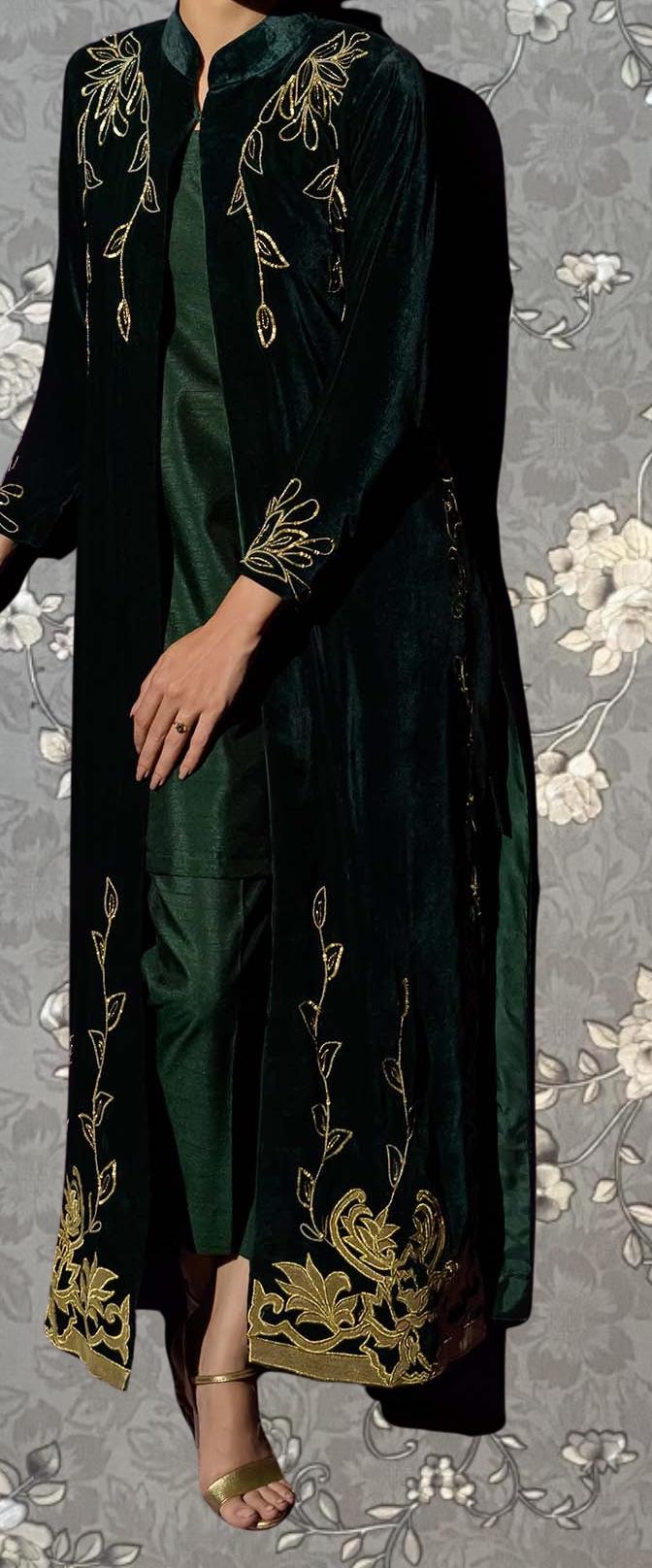 A person wearing a long, black velvet coat with gold embroidered designs on the sleeves and hem.