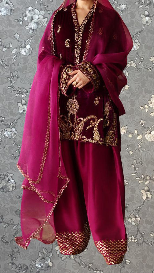 A person wearing a traditional red and gold outfit with intricate embroidery and a matching shawl.