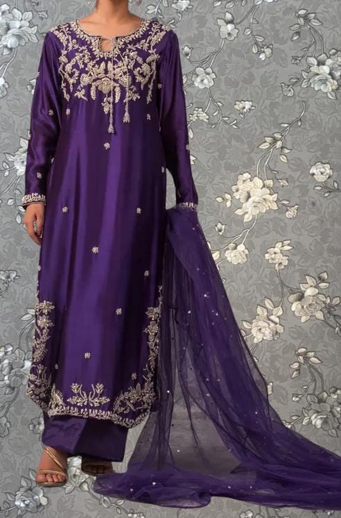 A person wearing a long purple dress with intricate embroidery and a matching purple shawl draped over their shoulders.