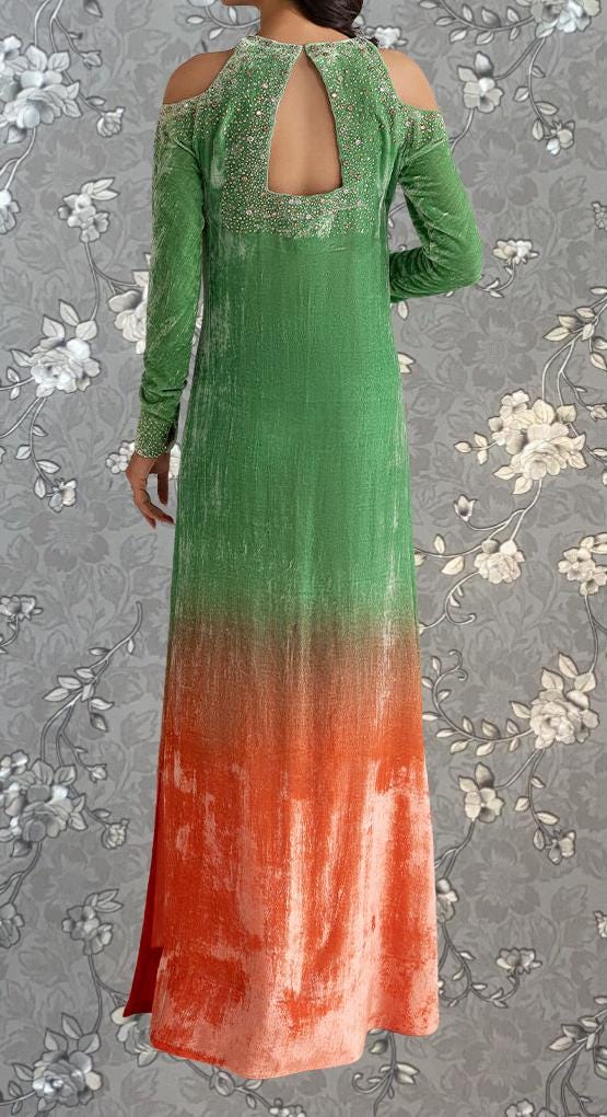 a woman wearing a long, green dress with a floral pattern. The dress has a high neckline and long sleeves, and the fabric appears to be a blend of green and orange colors. The woman is standing against a gray floral background, which complements the overall design of the dress.