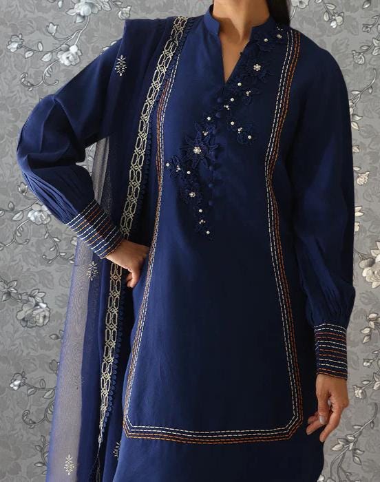 A person wearing a navy blue dress with intricate embroidery and a matching shawl.