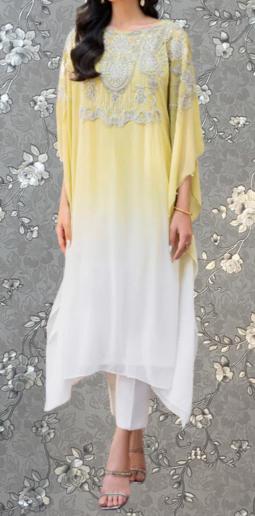 A woman wearing a yellow and white dress with intricate embroidery stands against a gray floral background.