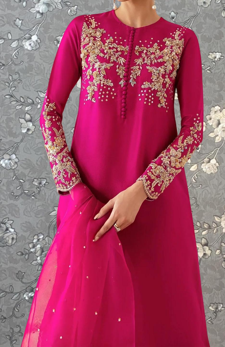 A woman wearing a long pink dress with intricate gold embroidery and a matching pink shawl.