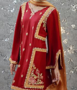 A red and gold dress with intricate embroidery and gold trim, displayed against a gray floral background.