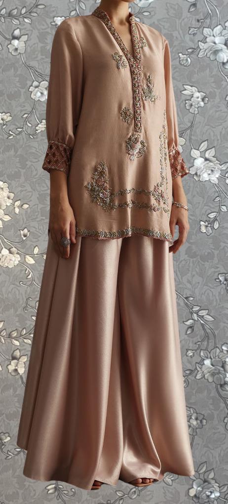 A woman wearing a long, beige dress with intricate embroidery and a high collar.