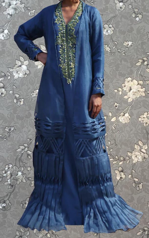 A person wearing a long, blue dress with intricate embroidery and a high collar.