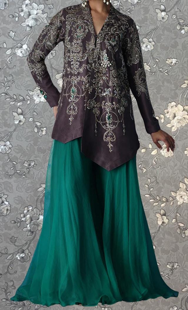 A woman wearing a long, dark purple jacket with intricate embroidery and a matching green skirt.