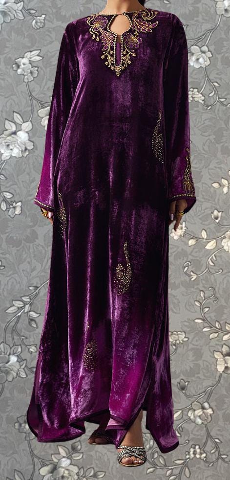 A person wearing a long, purple velvet dress with intricate gold embroidery on the neckline and sleeves.
