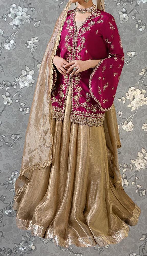 A woman wearing a long, gold and red dress with a matching gold shawl, standing against a gray floral background.