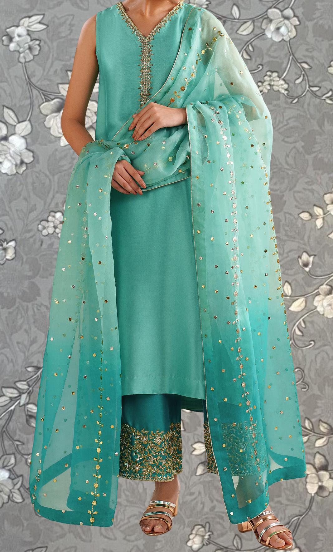 A woman wearing a turquoise dress with gold embroidery and a matching turquoise shawl with gold sequins.