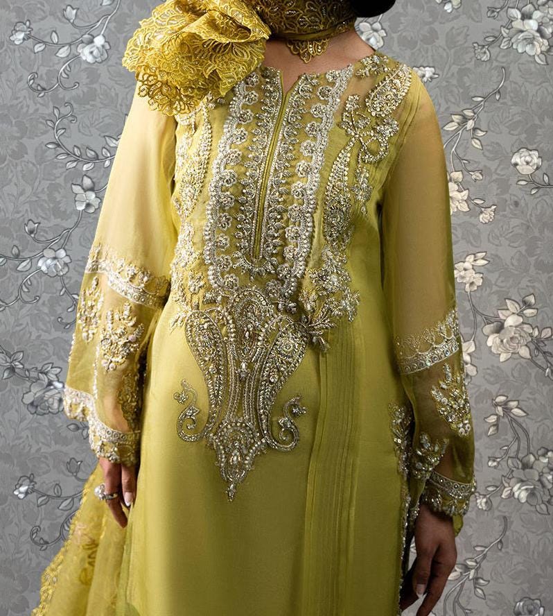 A woman wearing a yellow dress with intricate embroidery and a matching yellow scarf.
