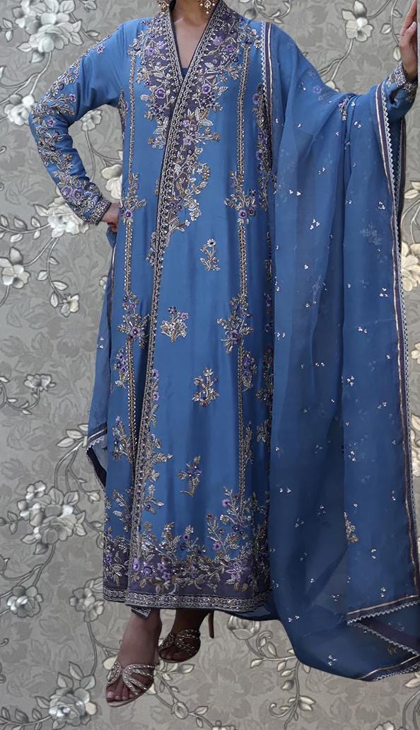 A person wearing a long, blue dress with intricate embroidery and a matching blue shawl.