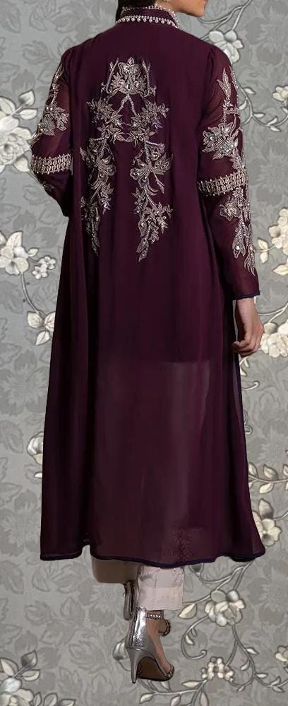 a person wearing a long, burgundy-colored coat with intricate embroidered designs on the back.