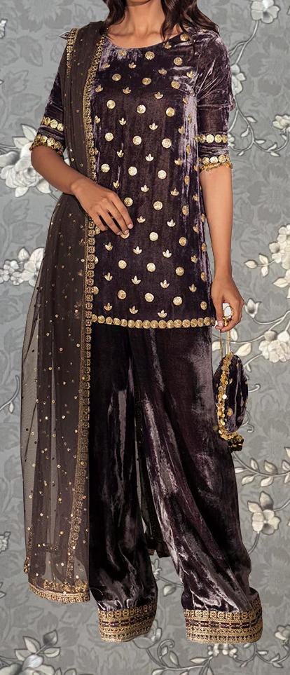 A woman wearing a purple velvet dress with gold polka dots and a matching shawl. She is holding a small purse in her hand.