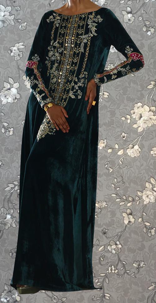 A person wearing a long, dark green velvet dress with intricate gold embroidery and floral patterns.