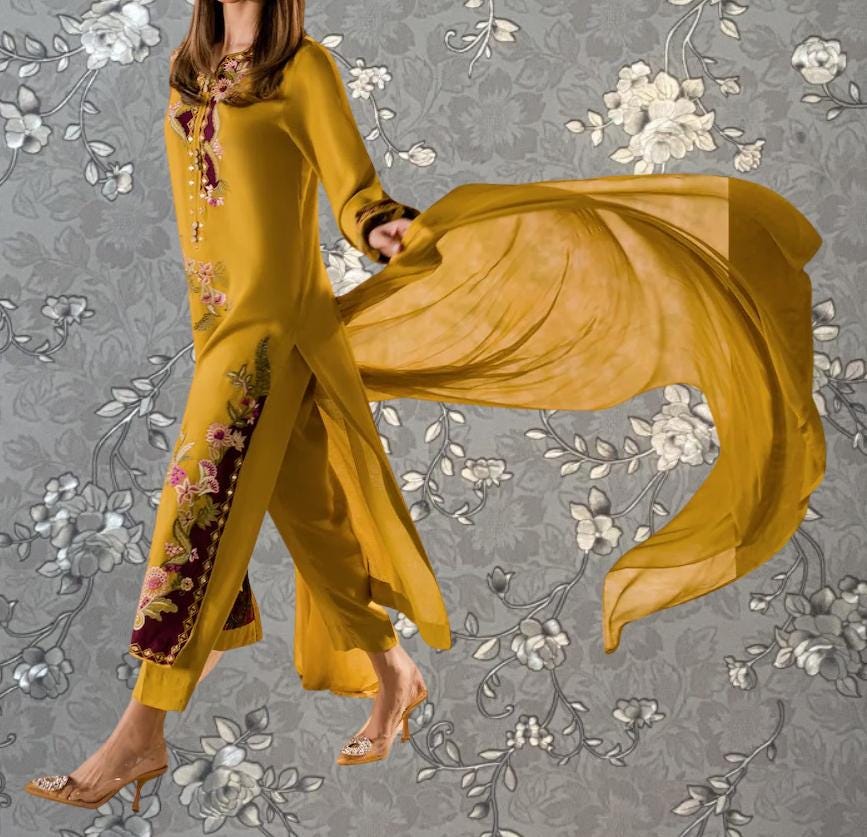 A woman wearing a yellow dress with floral embroidery and a flowing yellow shawl is shown against a gray floral background.