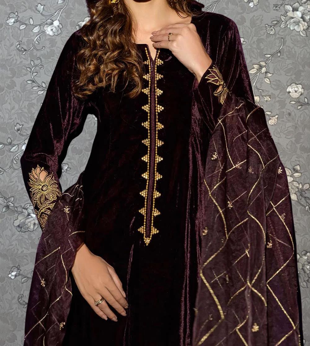 A woman wearing a long, burgundy velvet dress with gold embroidery and a matching shawl.