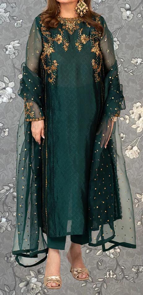 A woman wearing a green dress with gold embroidery and a matching green shawl.