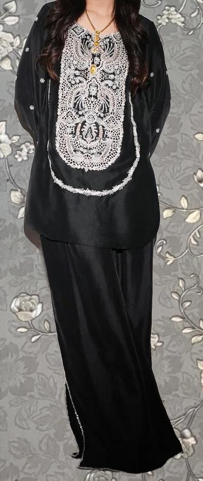 A woman wearing a black dress with a white lace pattern on the front.