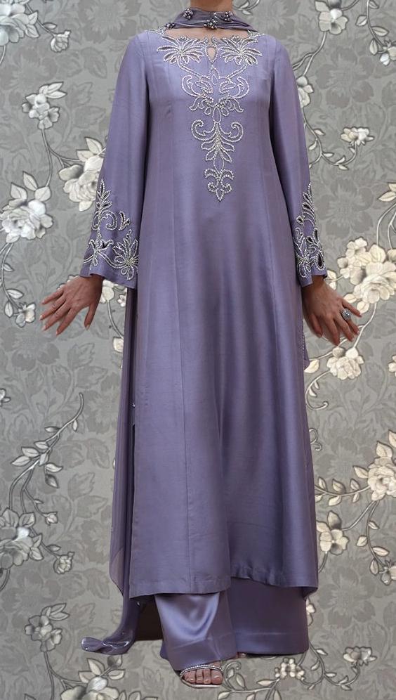 A woman wearing a long, purple dress with intricate embroidered designs on the bodice and sleeves.