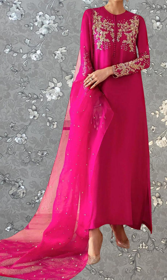 A woman wearing a long pink dress with intricate embroidery and a matching pink shawl.