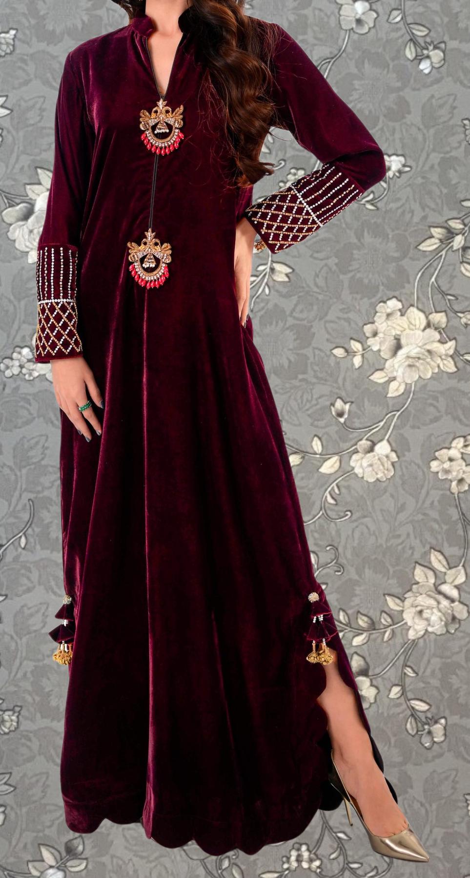 A woman wearing a long, burgundy velvet dress with intricate embroidery and tassels on the sleeves and hem.