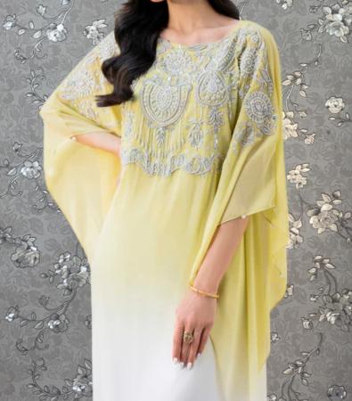 A woman wearing a yellow dress with intricate embroidery and a flowing, draped design.