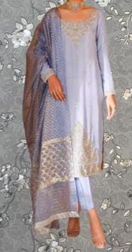 A woman wearing a long, light blue dress with gold embroidery and a matching shawl.