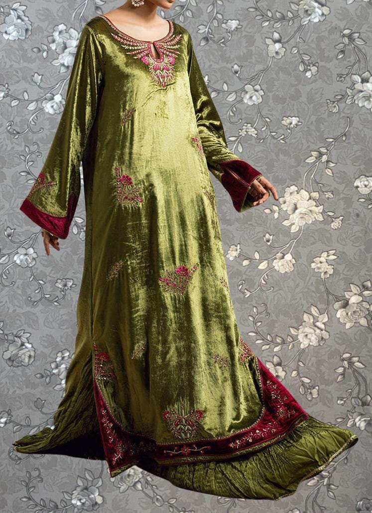 A woman wearing a long, green dress with red trim and floral embroidery.
