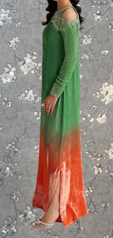 A woman wearing a long, green dress with a floral pattern and a high slit on the side.
