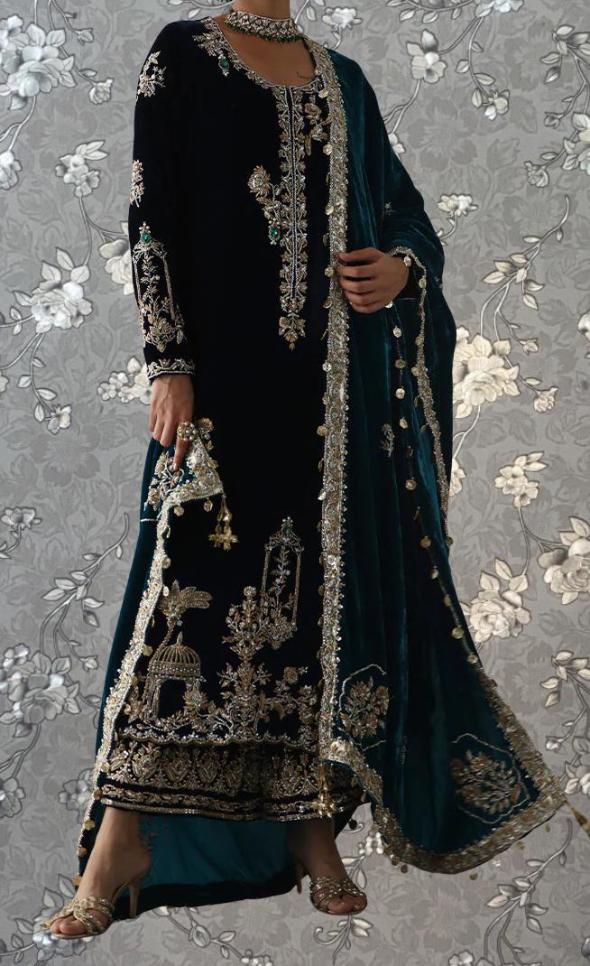A person wearing an ornate, black and gold dress with intricate embroidery and a matching green shawl.