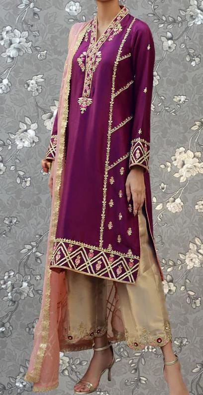 A person wearing a purple and gold dress with intricate embroidery and a matching shawl.