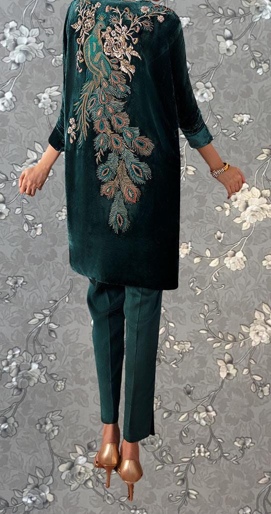 a person wearing a green velvet dress with intricate embroidered designs, including a peacock motif, and gold high heels.