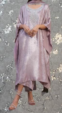 A woman wearing a long, flowing purple dress with a floral pattern on the background.