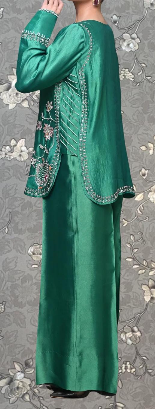 A person wearing a long, green dress with intricate embroidery and a matching jacket.